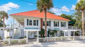 A two-story house with a red roof, white exterior, and a covered porch. - Tybreeza A by Tybee Vacation Rentals (Tybee Island)