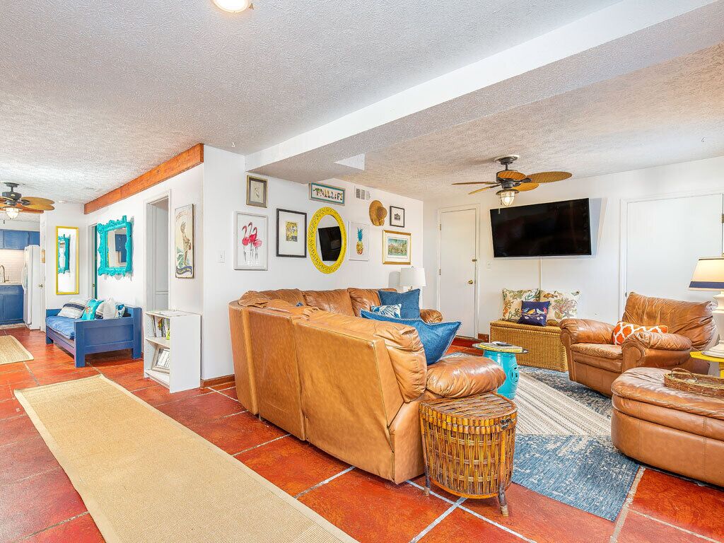 A spacious living room with a large brown leather sofa, a television, and various wall decorations.