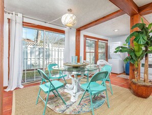 Enjoy meals in this dining area with a round table and four chairs, surrounded by a large potted plant and a ceiling fan.