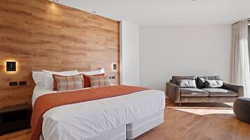 Un dormitorio moderno con una cama grande, un sofá y paneles de madera en la pared.