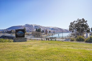 A sign for Grand Suites in Lake Tahoe, a mountainous backdrop, and a view of the lake.