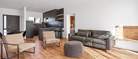 A modern living room with a sofa, chairs, and ottoman.