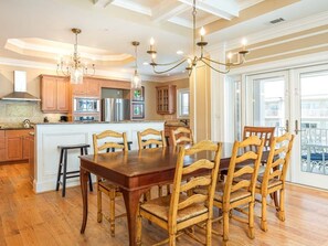 Una cocina amplia con armarios de madera, una isla central y un comedor con una gran mesa y sillas de madera.