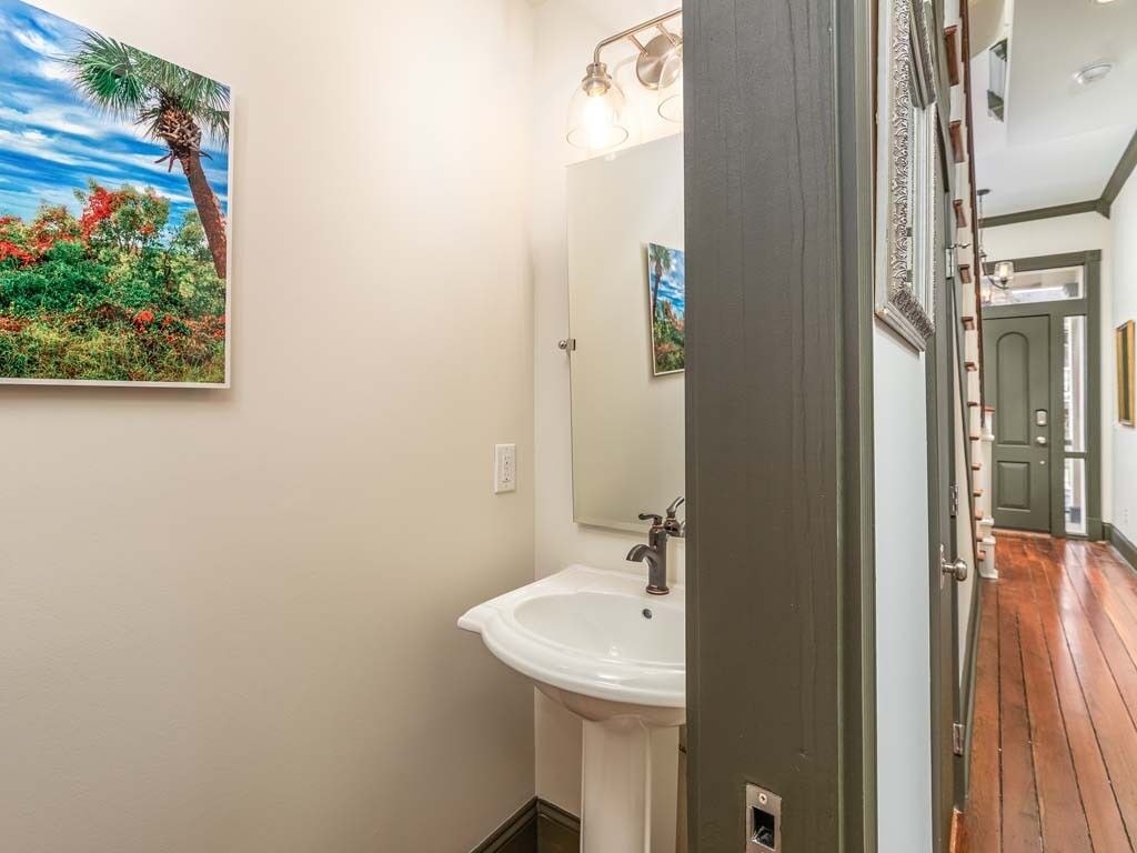 A bathroom with a white sink, a mirror, and a painting of a tropical scene.