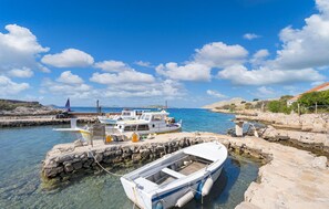 A coastal marina with boats docked, clear water, and rocky terrain.