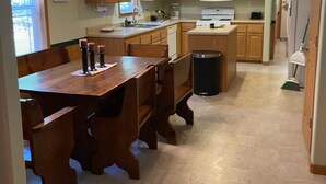 Una cocina amplia con armarios de madera, una isla central y un comedor con sillas de madera.
