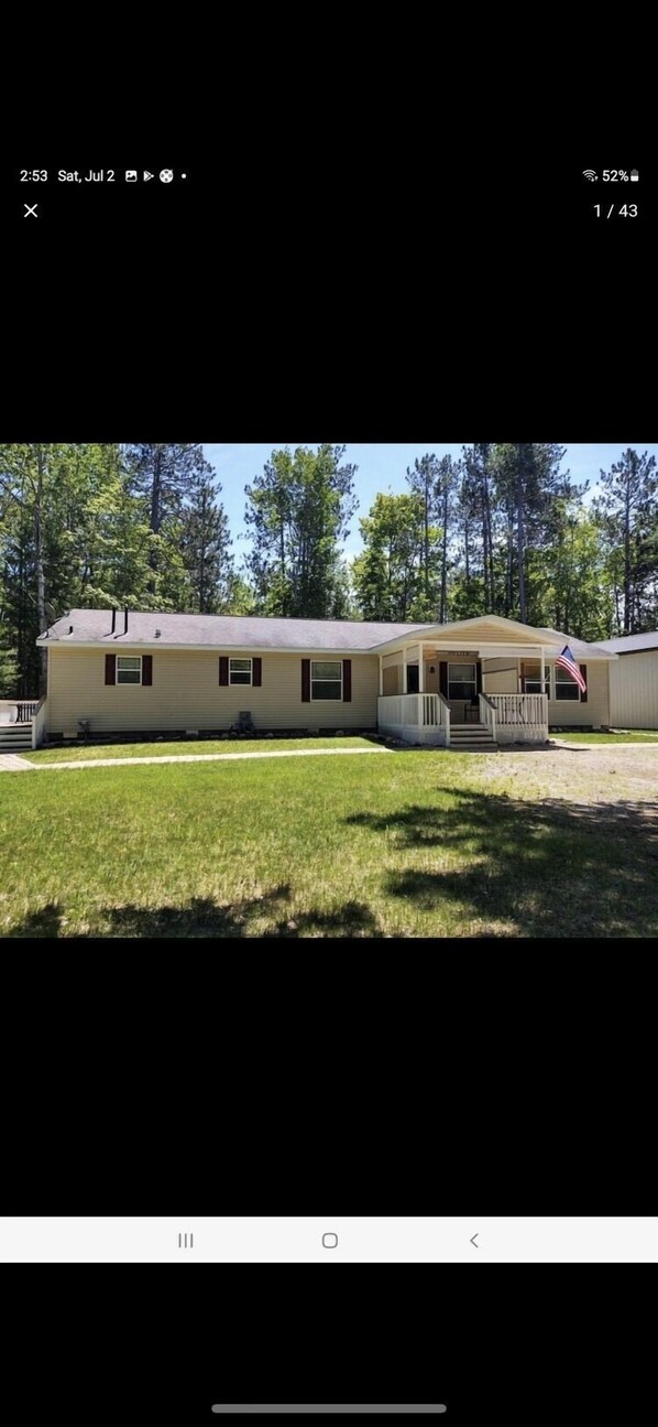 A single-story house with a front porch, a small deck, and an American flag.
