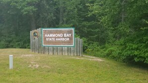 Un letrero de madera con el texto 'Hammond Bay State Harbor' y el logotipo del Departamento de Recursos Naturales.