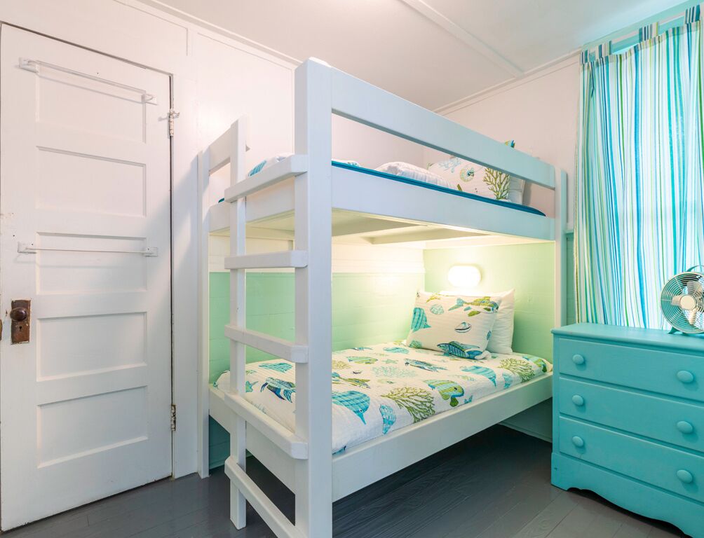 A bunk bed with a ladder, a night light, and a dresser with drawers.