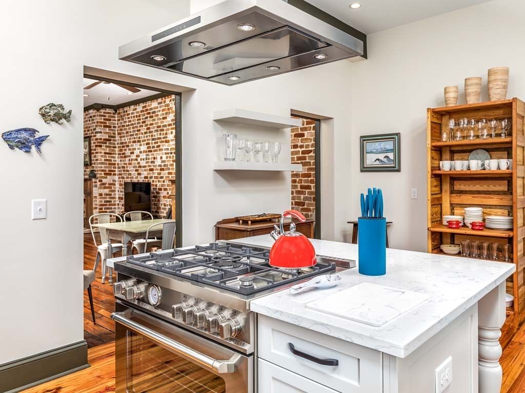 Uma cozinha moderna com fogão a gás, chaleira vermelha e bancada de mármore.