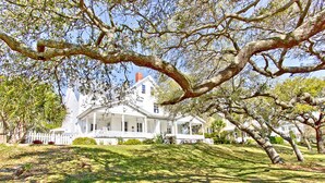 Un grand bâtiment blanc, doté d’un porche imposant et d’un mât pour drapeau, entouré de pelouses et d’arbres bien entretenus.