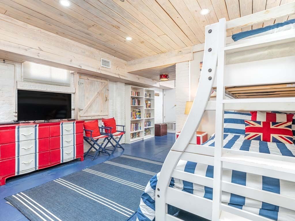 Une chambre avec un lit superposé, une armoire rouge et blanche, un téléviseur et une bibliothèque.