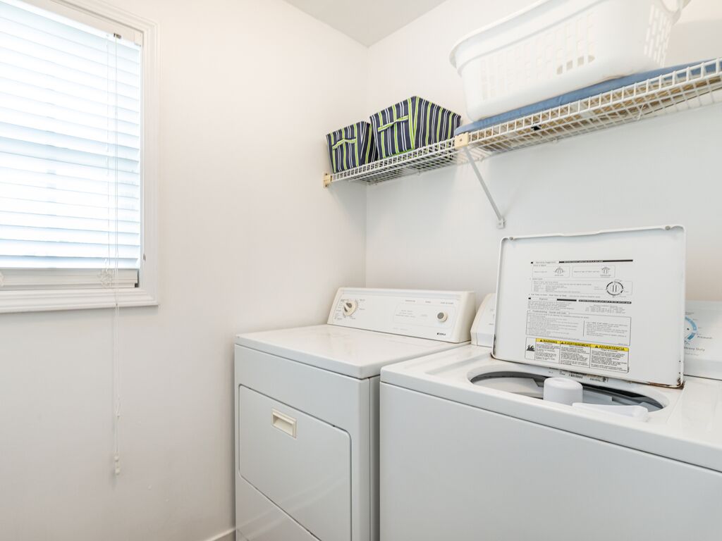 A laundry area with a washing machine, dryer, and storage shelves.
