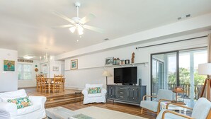 Amplia sala de estar con ventilador de techo, televisión y comedor con muebles de madera.