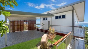 A modern house with a covered patio, a stone feature, and a view of the sea. - Searenity on Castle hill (Castle Hill)
