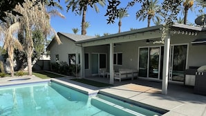 A modern house with a swimming pool, covered patio, and palm trees. - Luxurious modern 3-bedroom plus den home w/ pool & hot tub (Phoenix)