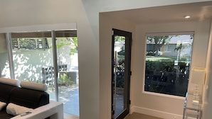 A modern living room with a sofa, a glass door leading outside, and a view of the backyard. - Luxurious modern 3-bedroom plus den home w/ pool & hot tub (Phoenix)