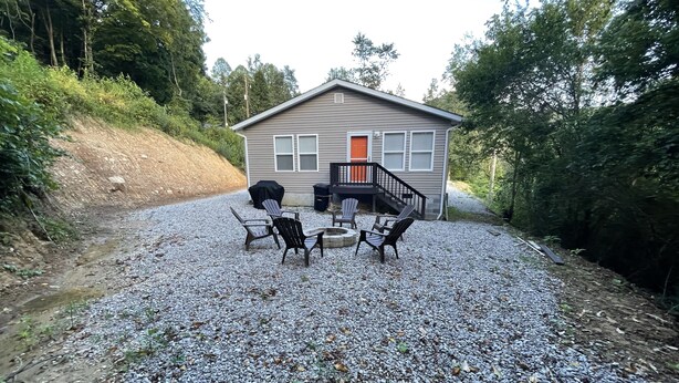 A cabin with a gravel patio, outdoor seating, and a covered grill area.