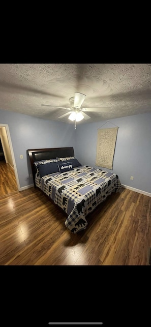 Relax in this inviting bedroom with a comfortable bed, patterned bedspread, and a decorative wall hanging.