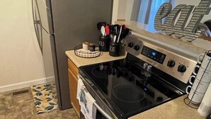 A kitchen with a refrigerator, stove, and various kitchen utensils.