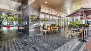 Ett modernt kafé med glasväggar, kakelgolv och sittplatser utomhus.