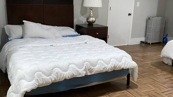 A bedroom with a bed, a nightstand, a lamp, and a radiator.