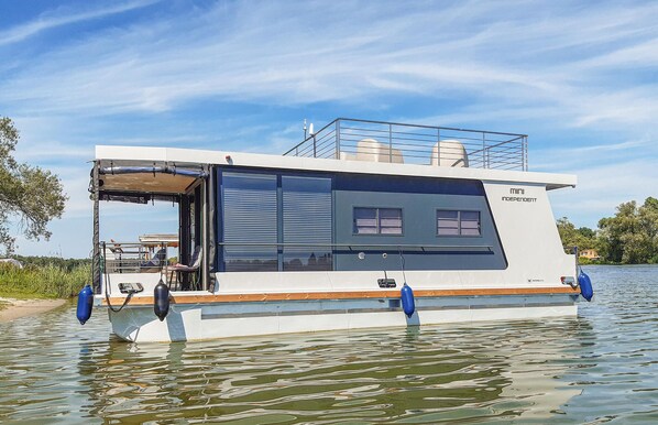 A modern houseboat with a covered deck area, a small window, and a name "mini INDEPENDENT" on the side. - 1 bedroom beach front ship in Havelsee OT Kützkow (Havelsee OT Kützkow)