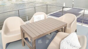 Ein Balkon mit Tisch, zwei Stühlen und Geländern, sowie Solarpanels.