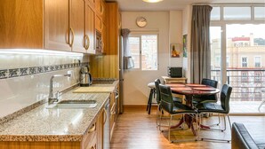 A modern kitchen with granite countertops, wooden cabinets, and a dining area with a round table and chairs. - Amazing apartment in Málaga with WiFi (Málaga)