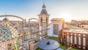 Eine Dachterrasse mit Blick auf die Stadtlandschaft, darunter ein Kirchturm und eine Turmuhr.