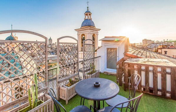 A rooftop terrace with a view of a cityscape, including a church tower and a clock. - Beautiful apartment in Genova with WiFi (Genova)