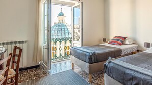Ein Hotelzimmer mit zwei Betten, einem Esstisch und Blick auf ein Gebäude mit einer Kuppel.