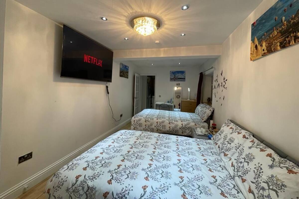 Een hotelkamer met twee bedden, een aan de muur bevestigde televisie en een kroonluchter.
