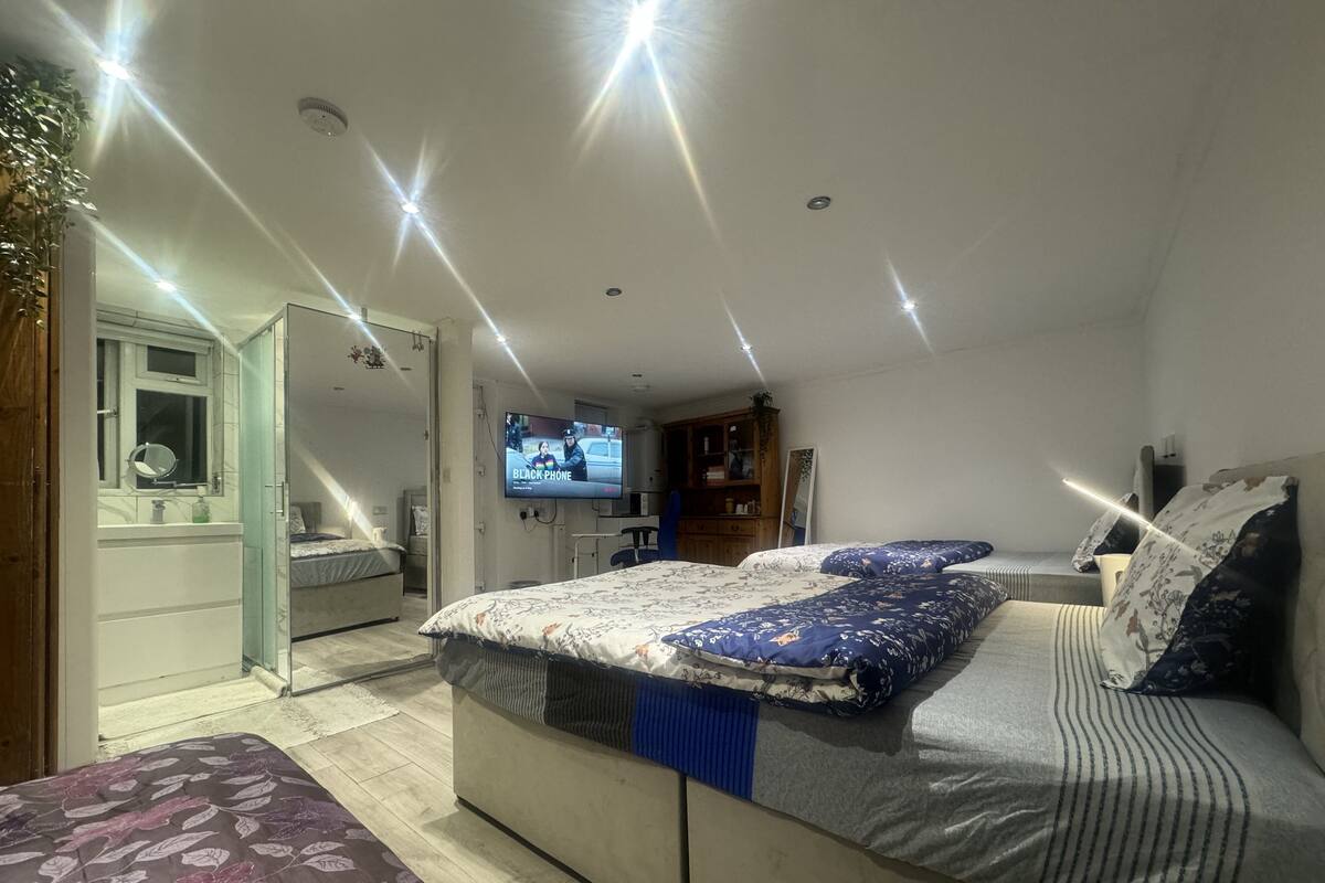 Een moderne slaapkamer met een groot bed, een aan de muur bevestigde televisie en een badkamer door een open deur zichtbaar.