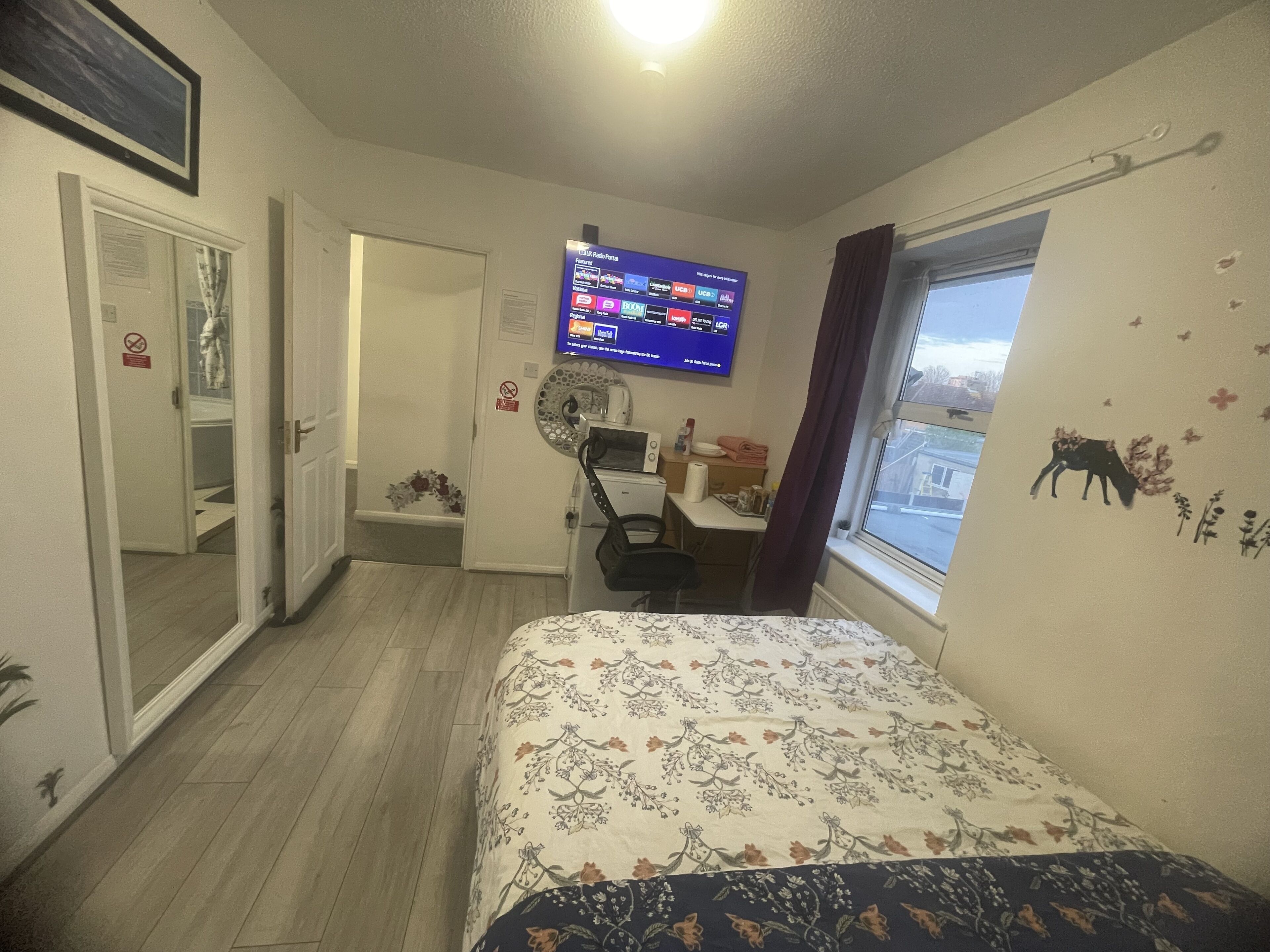 Ein Schlafzimmer mit Bett, Schreibtisch, Stuhl, Fernseher und Fenster mit Aussicht.