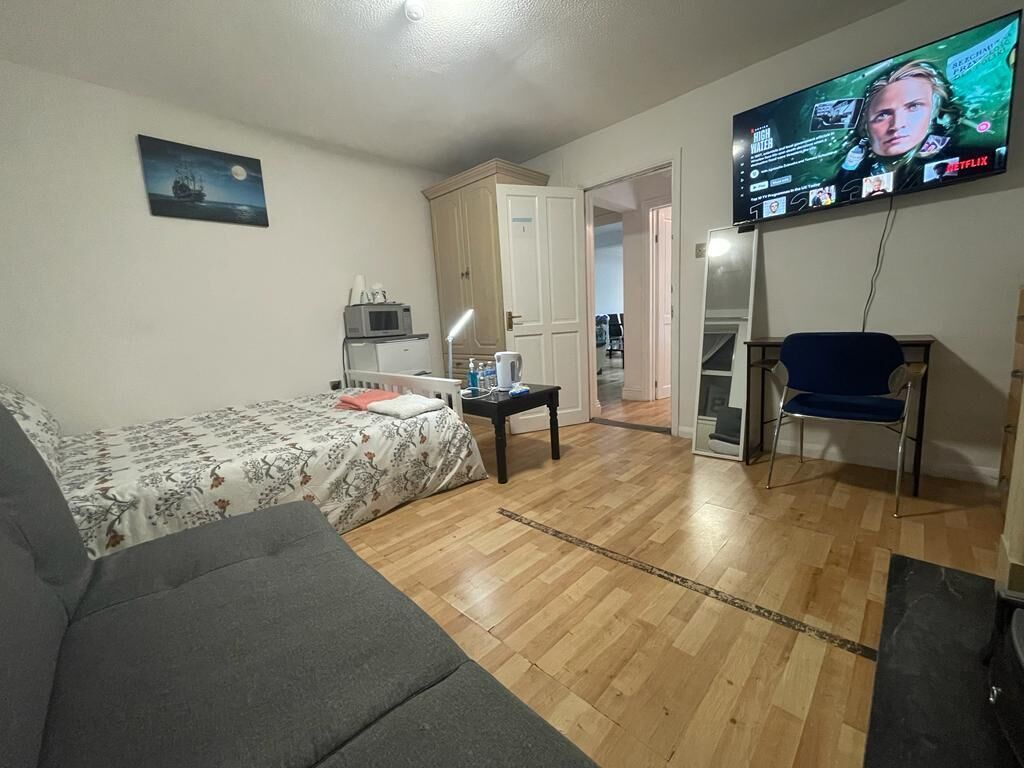 Una habitación con cama, escritorio, silla, televisor y armario.