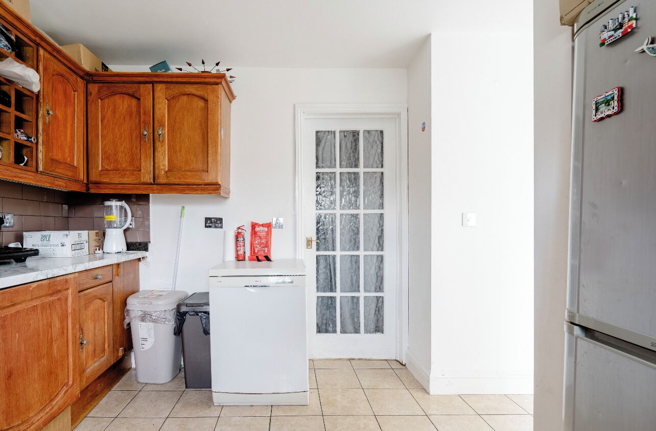Une cuisine compacte avec des meubles en bois, un réfrigérateur blanc et une porte dotée de panneaux en verre dépoli.