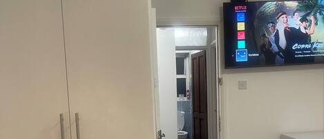 Ein Hotelzimmer mit Bett, einem an der Wand montierten Fernseher, einem Kleiderschrank und einer Tür zum Badezimmer.