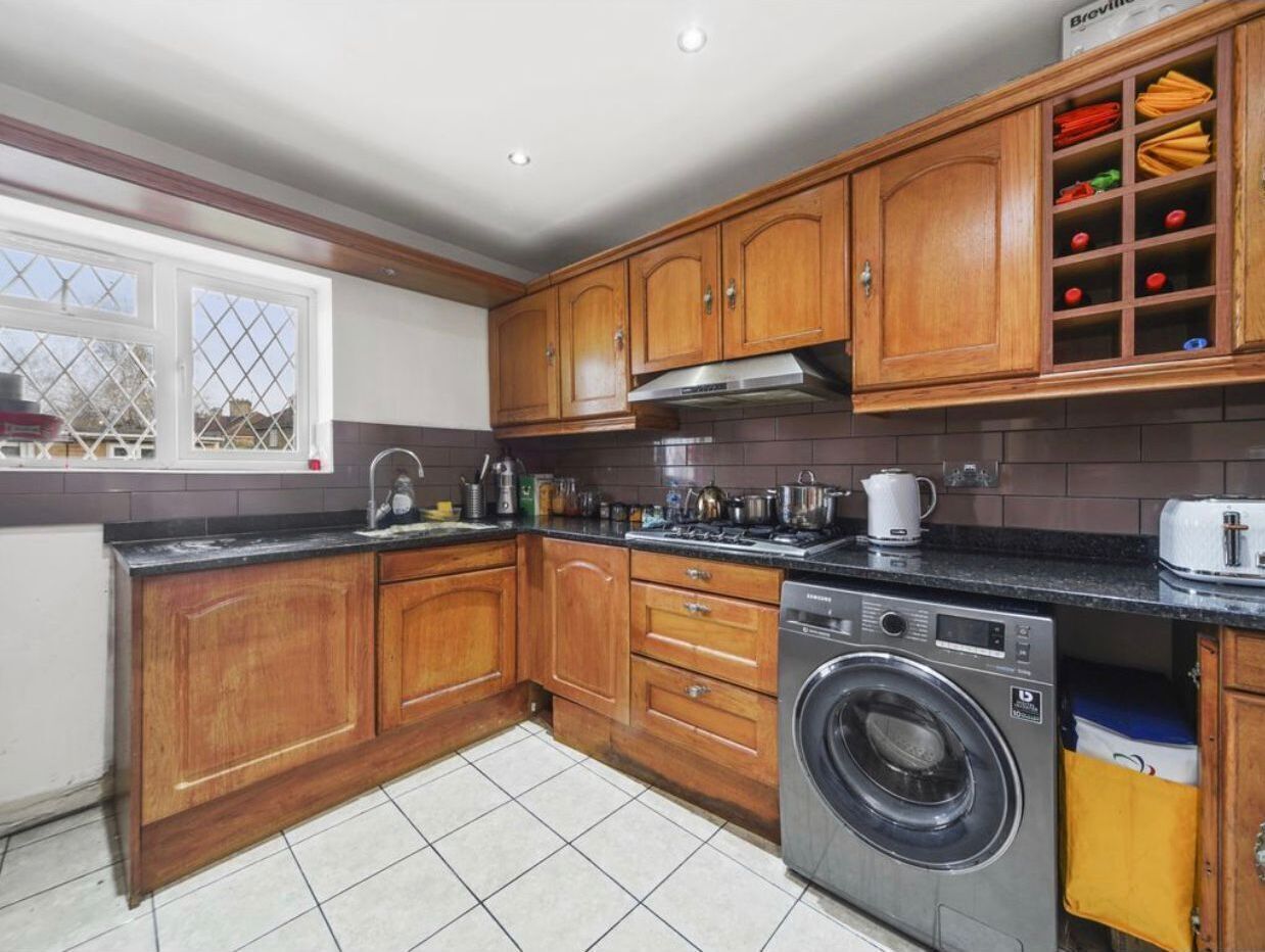Cocina compacta con armarios de madera, lavadora integrada y ventana con vistas.