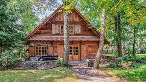 Eine Holzhütte mit Steinuntergrund, umgeben von Bäumen und einer Steinmauer.