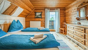 A wooden cabin room with two beds, a dresser, a chair, and a window with a view of mountains. - Ferienhaus mit Ausblick (Bad Goisern am Hallstät)