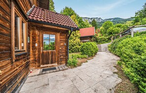 A wooden cabin with a tiled roof, a stone pathway, and a view of a mountainous landscape. - Ferienhaus mit Ausblick (Bad Goisern am Hallstät)