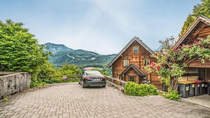 A wooden cabin with a car parked in front, surrounded by greenery and mountains in the background. - Ferienhaus mit Ausblick (Bad Goisern am Hallstät)