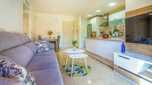 A modern living room with a sofa, a small round table, and a TV. - Beach front apartment in Los Alcázares (Los Alcázares)
