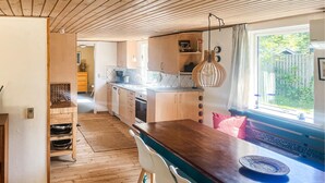 Eine moderne Küche mit Holzausstattung, einem Holzespeisetisch und Blick ins Freie.