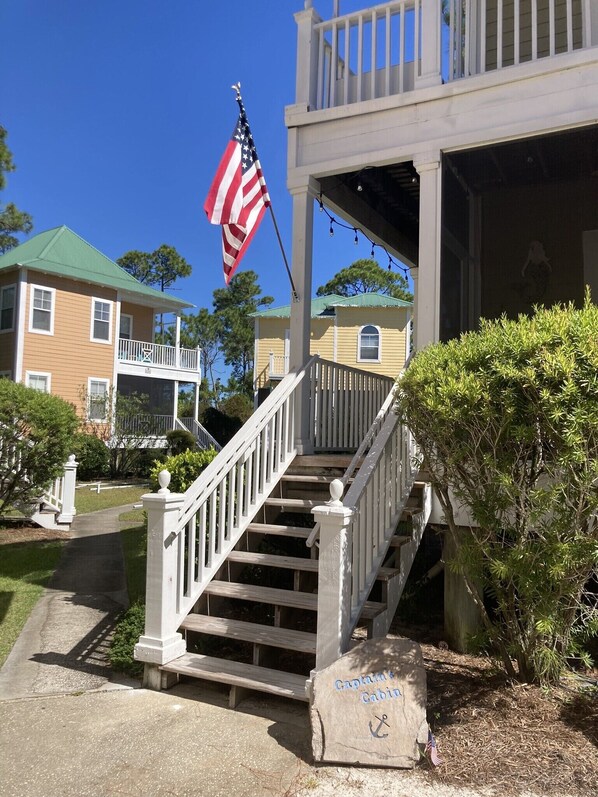 A two-story building with a porch and a flagpole with an American flag.