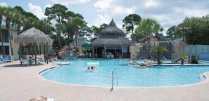 A swimming pool with lounge chairs and a thatched-roof structure.