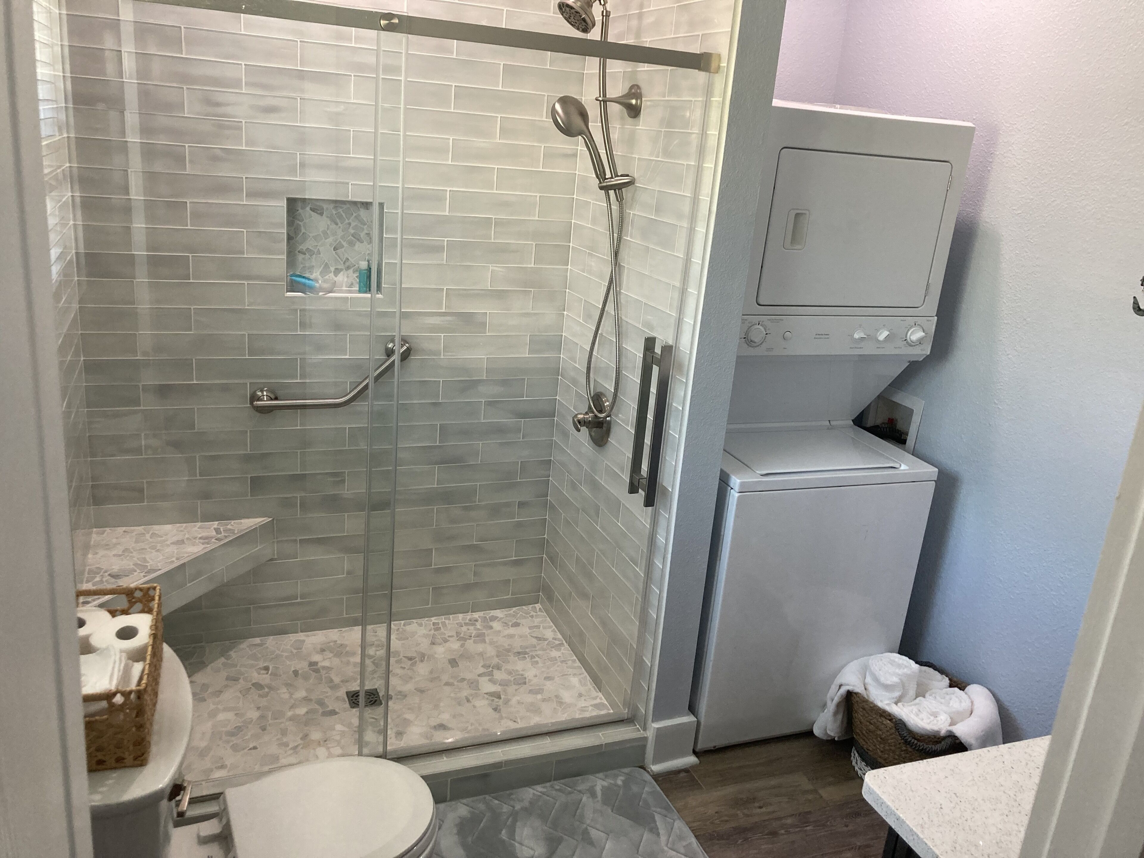 A small bathroom with a shower, toilet, and a washing machine.