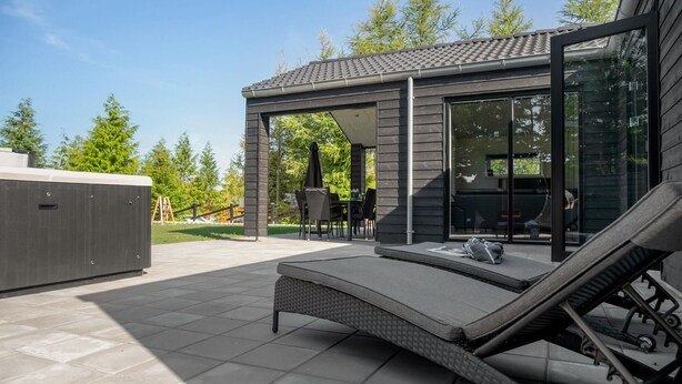 A modern outdoor patio with a hot tub, seating area, and a covered dining space. - Lovely home in Glesborg with sauna (Glesborg)