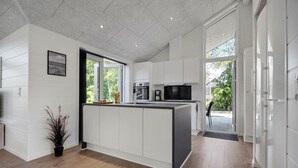 A modern kitchen with white cabinetry, a large island, and a view of the outdoors. - Lovely home in Glesborg with sauna (Glesborg)